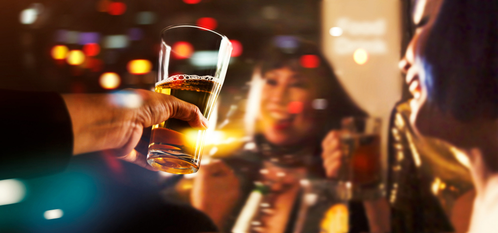 Friends enjoying drinks and conversation at a bar during a reunion on Thanksgiving Eve.